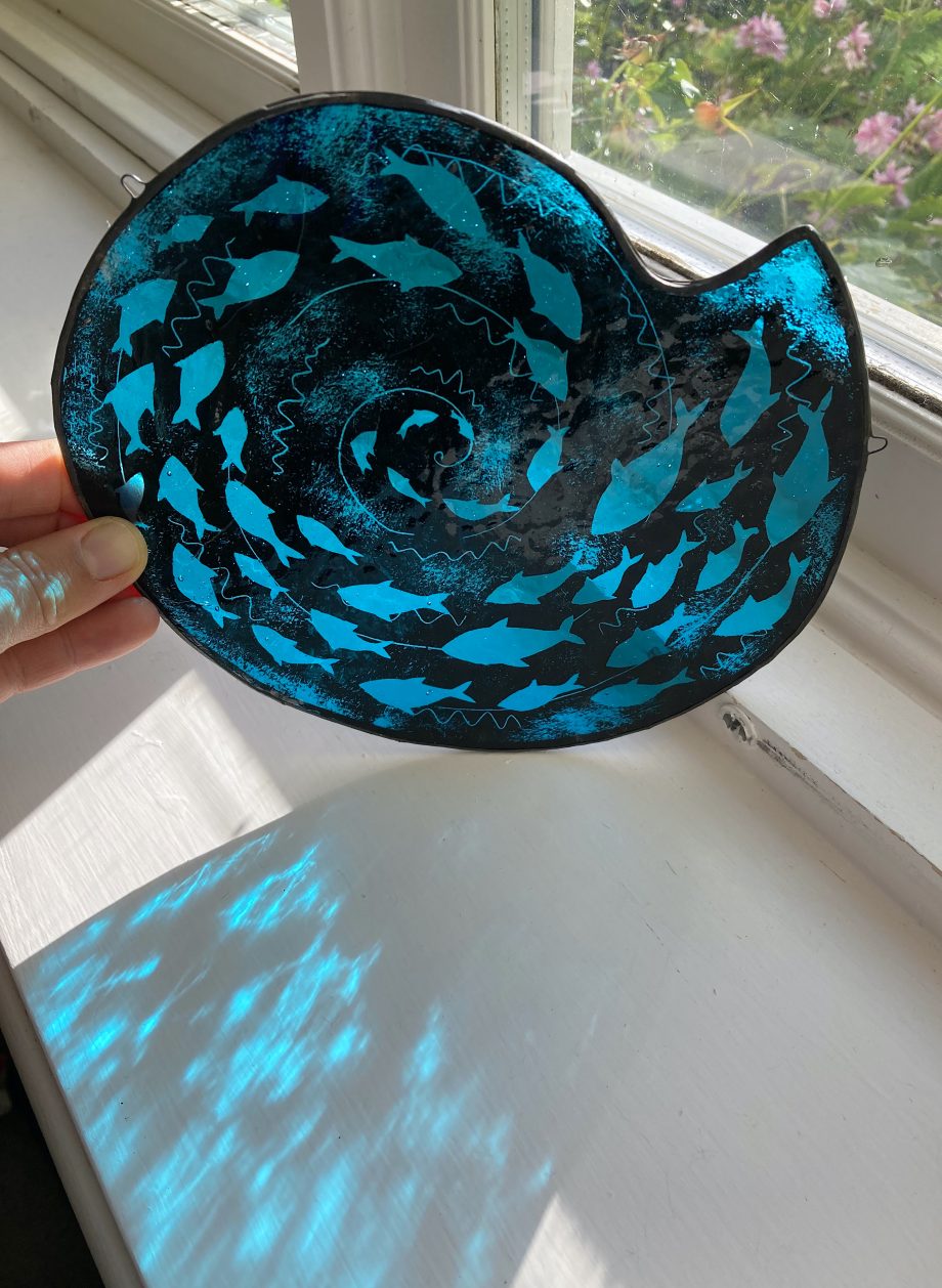Stained glass fish spiral at window
