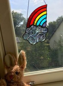 Stained glass sun catcher of rainbow and cloud on window